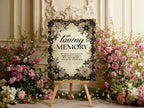 A decorative memorial sign on a wooden easel, surrounded by pink and white floral arrangements against an ornate cream-colored wall.