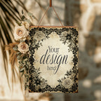A hanging decorative sign with a floral black-and-cream border and the text 'Your design here!'. The sign is styled with cream roses and dried grasses on the left, suspended by a brown cord against a warm, softly blurred background with palm leaves.