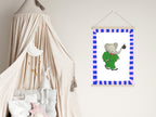 Framed picture of an elephant in a green outfit hanging on a wall next to a crib with canopy.