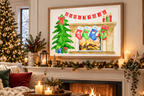 A framed Christmas art print hangs on a wall above a decorated fireplace mantel in a cozy living room. The artwork shows a green Christmas tree, a fireplace with four colorful stockings, candles, and a red banner.