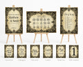 A coordinated wedding stationery set displayed on small wooden easels, including a guest book, unplugged sign, pick a seat sign, confetti sign, thank you sign, table numbers sign, and three matching printed cards. The design uses a distressed beige background with ornate black damask-style borders and elegant script text.