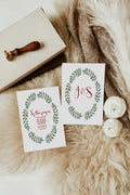 Two greeting cards with floral designs and 'J&S' on a textured surface with a stamp and flowers.