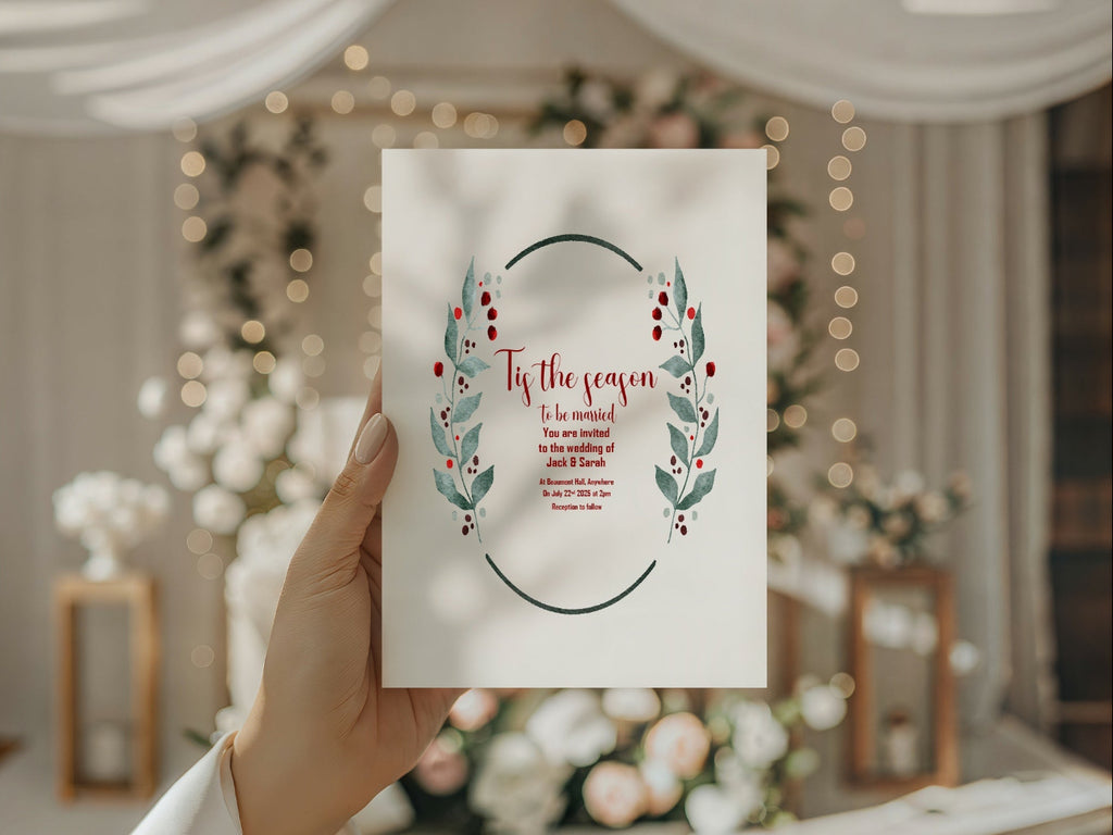 Hand holding a Christmas-themed invitation card with decorative wreath design against a festive background.