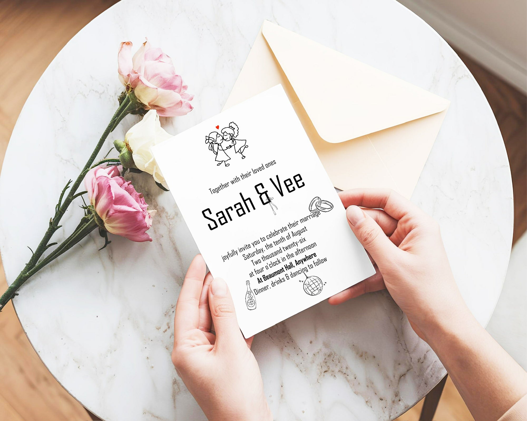 Hands holding a wedding invitation card with flowers on a marble surface