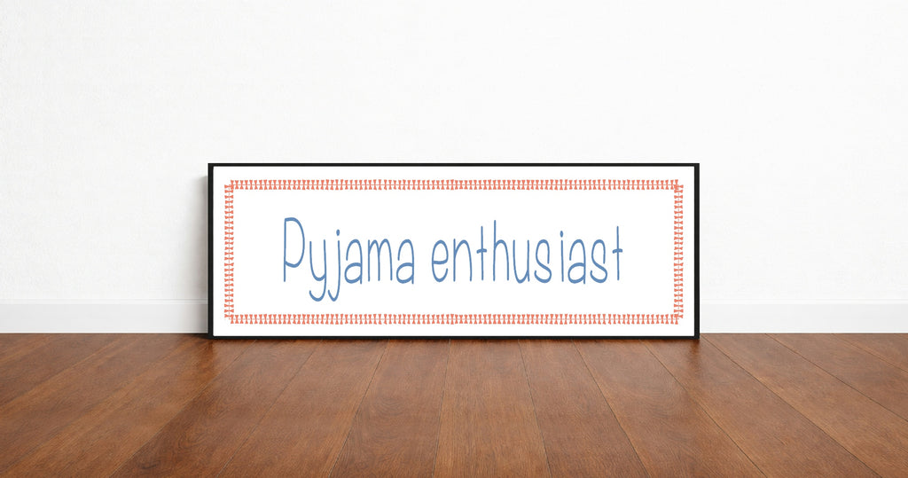Framed picture with 'Pyjama enthusiast' text on a wooden floor and white wall background