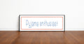 Framed picture with 'Pyjama enthusiast' text on a wooden floor and white wall background