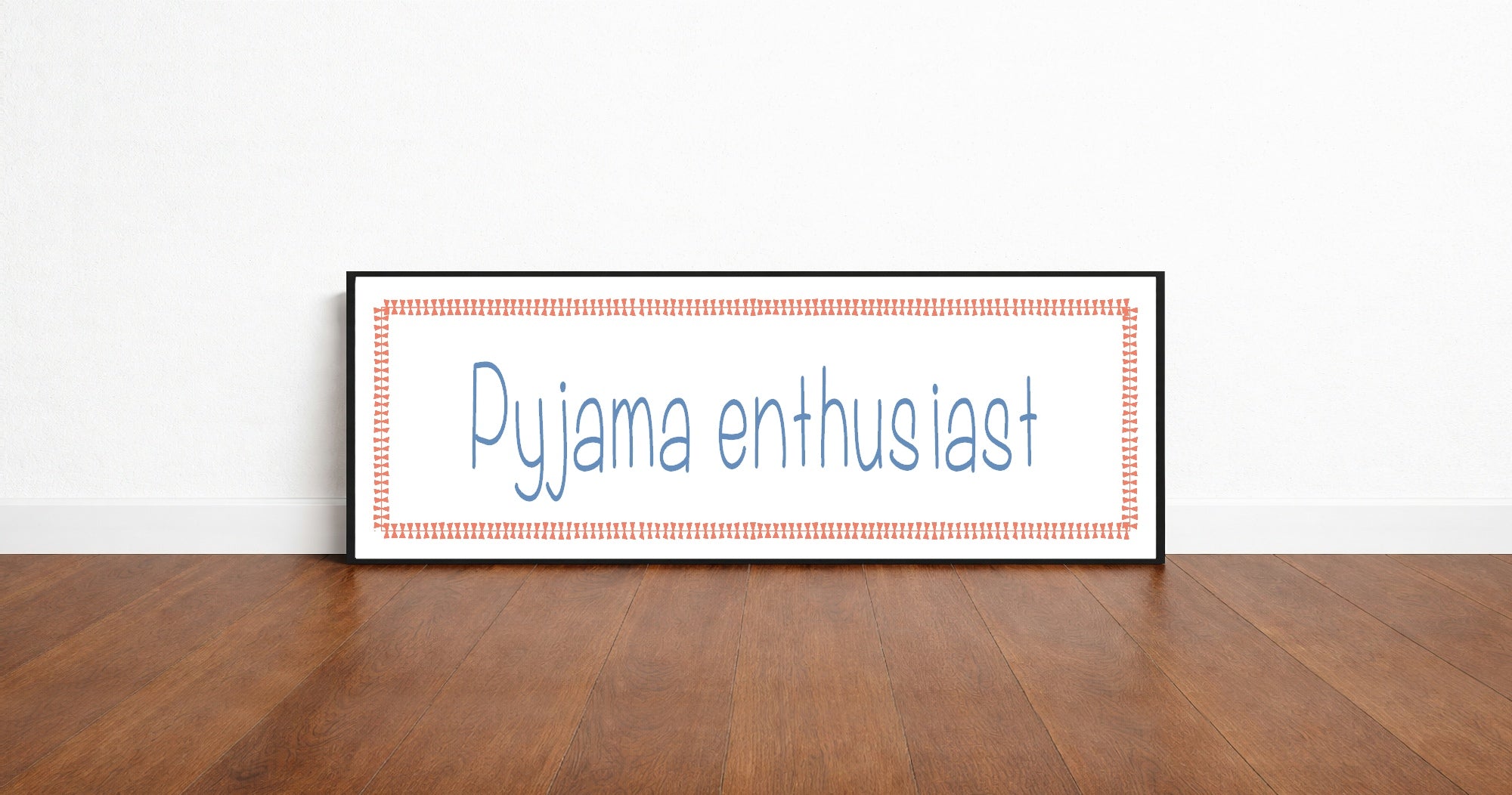 Framed picture with 'Pyjama enthusiast' text on a wooden floor and white wall background