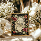 Decorative wedding sign with floral design surrounded by white flowers on a table.