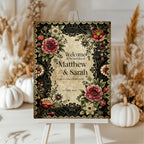 Decorative wedding invitation with floral design on an easel against a neutral background.