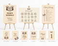 A coordinated wedding event planning kit displayed on wooden easels and cards, including a welcome sign, seating plan, order of the day, guest book, unplugged cards, confetti, thank you cards, and table numbers, all in a warm cream color with dark brown illustrations and text.