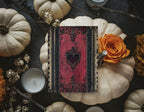 Red Spell Book invitation reverse with black heart motif beside pumpkins and an orange rose